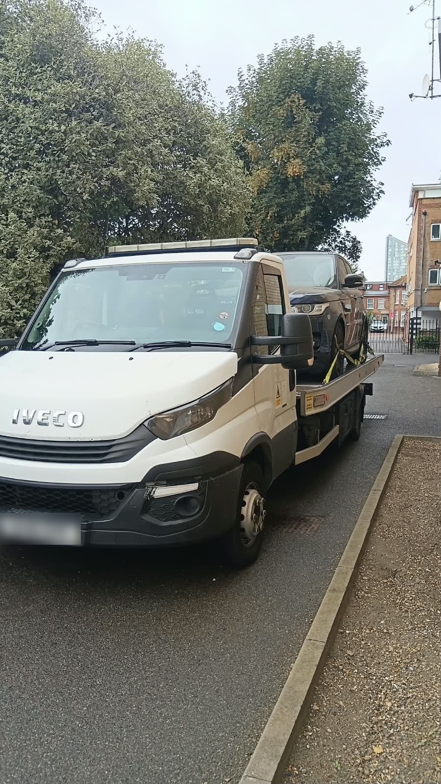 Iveco recovery truck carrying a vehicle on a quiet road