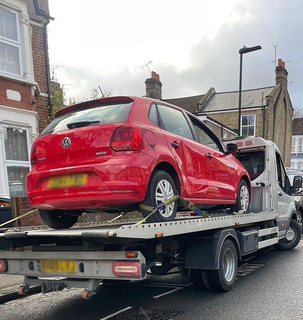 Red hatchback secured on a flatbed truck during car breakdown recovery