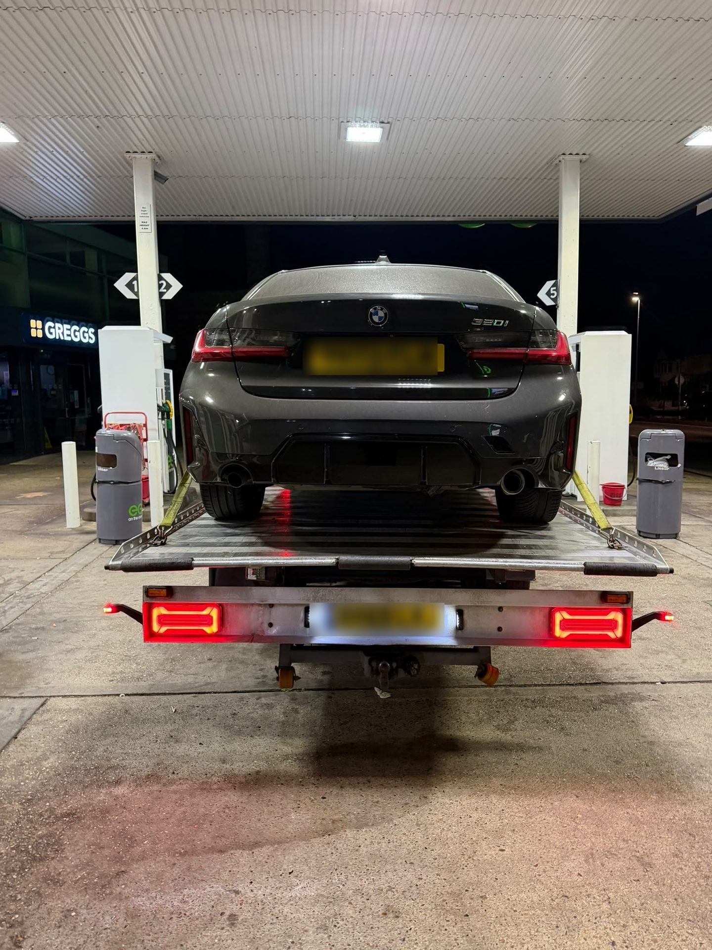 BMW loaded on a recovery truck under forecourt lights during an emergency call-out