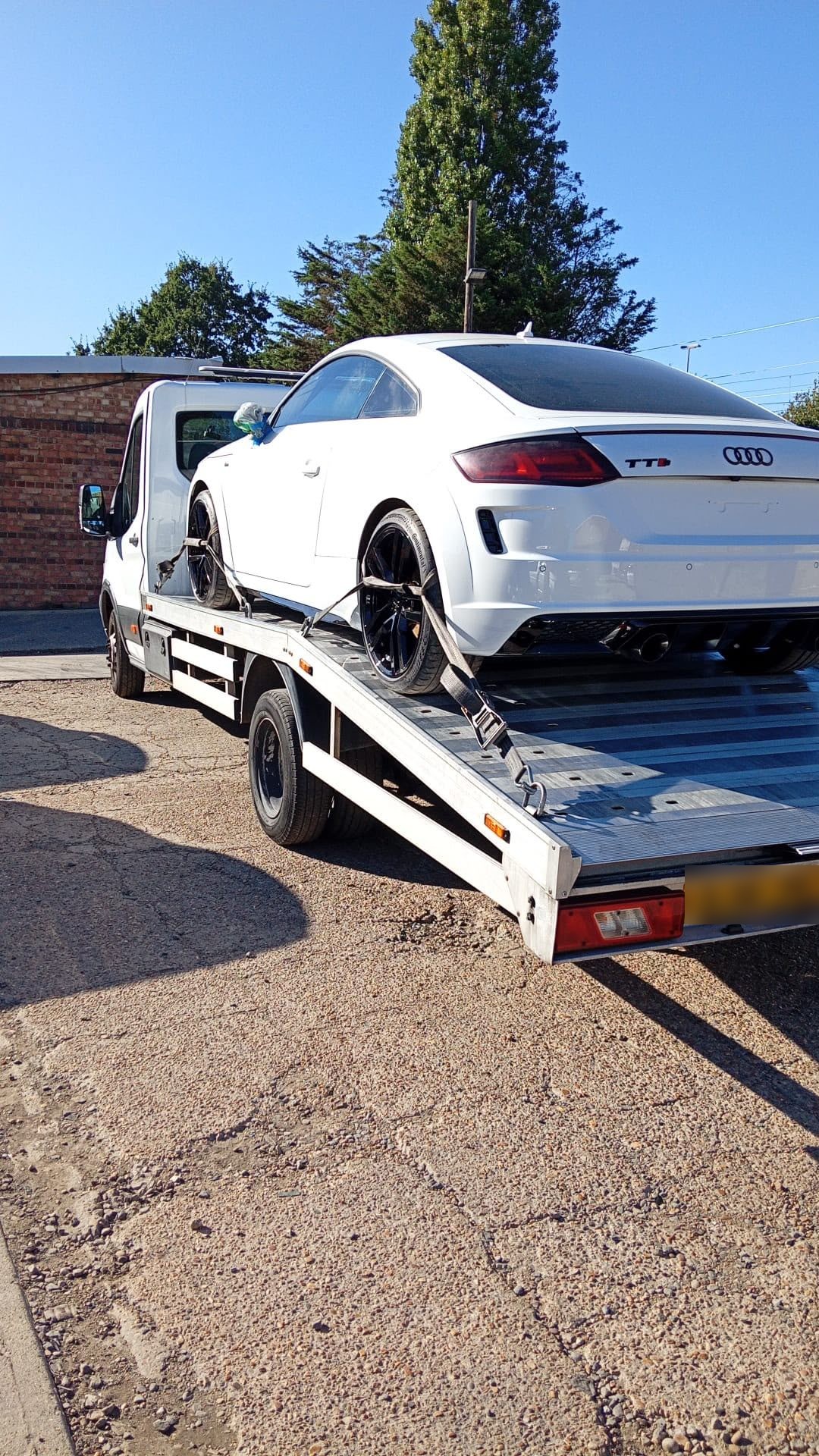 White Audi TT being loaded onto a truck for vehicle transportation