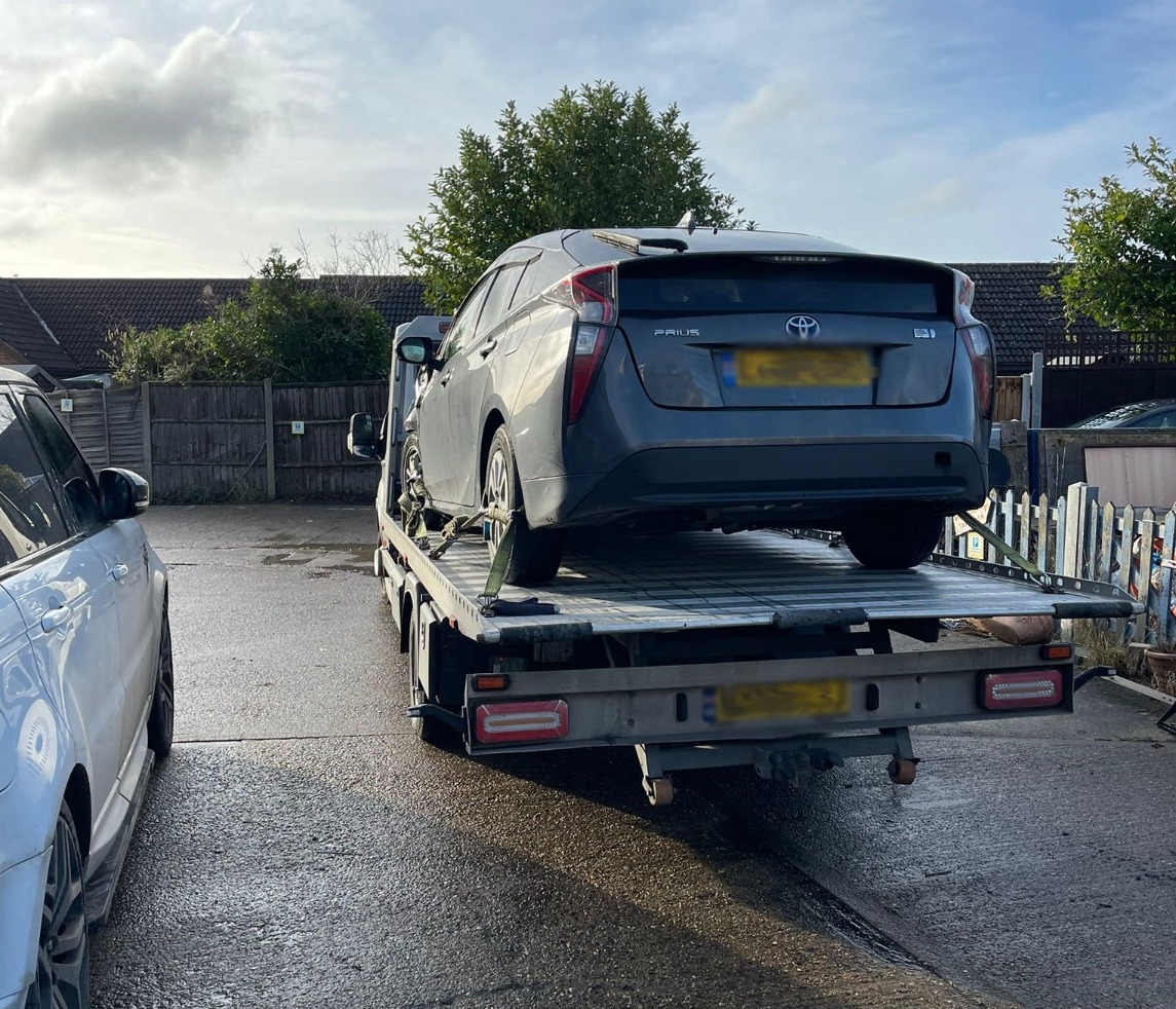 Grey Toyota Prius loaded on a flatbed recovery truck