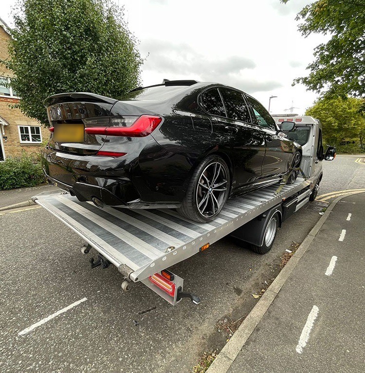 Black BMW saloon on a flatbed recovery truck in Barking