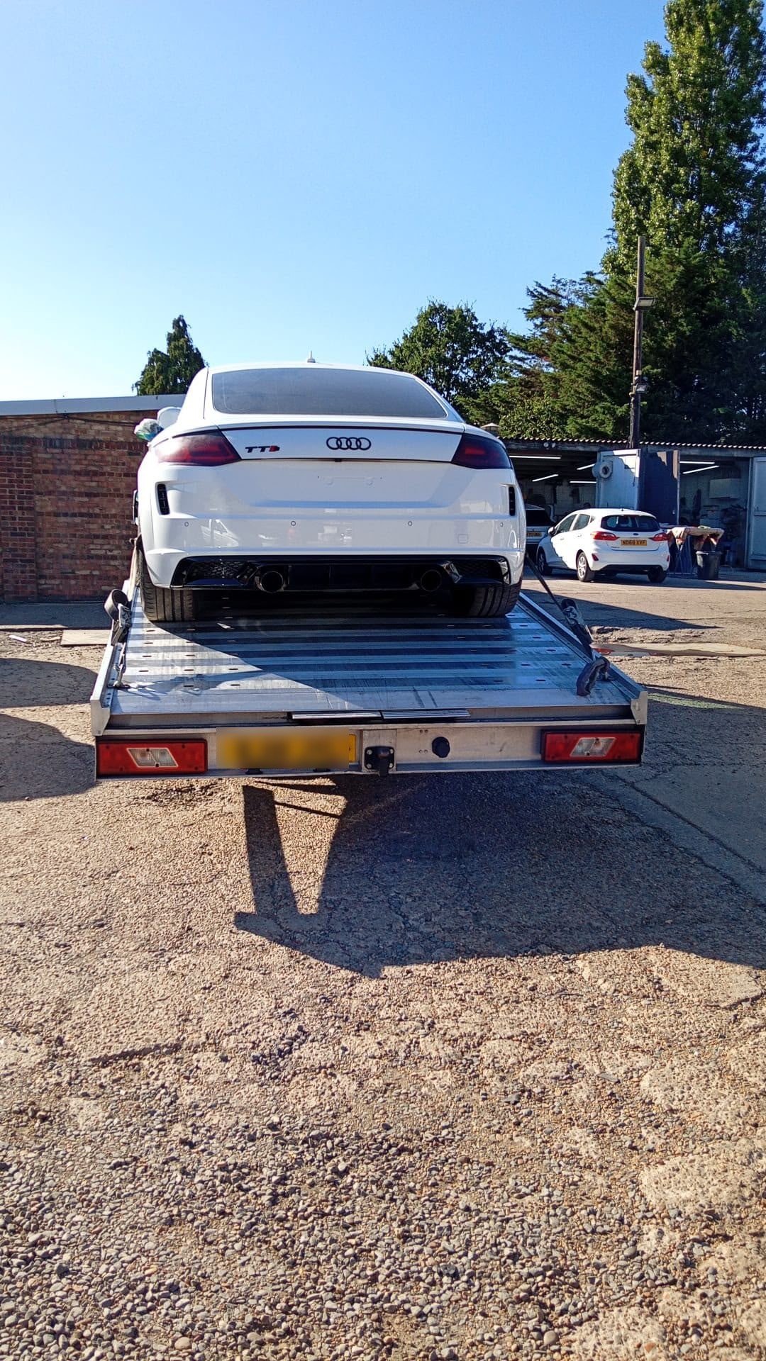 White Audi secured on a flatbed truck ready for transport